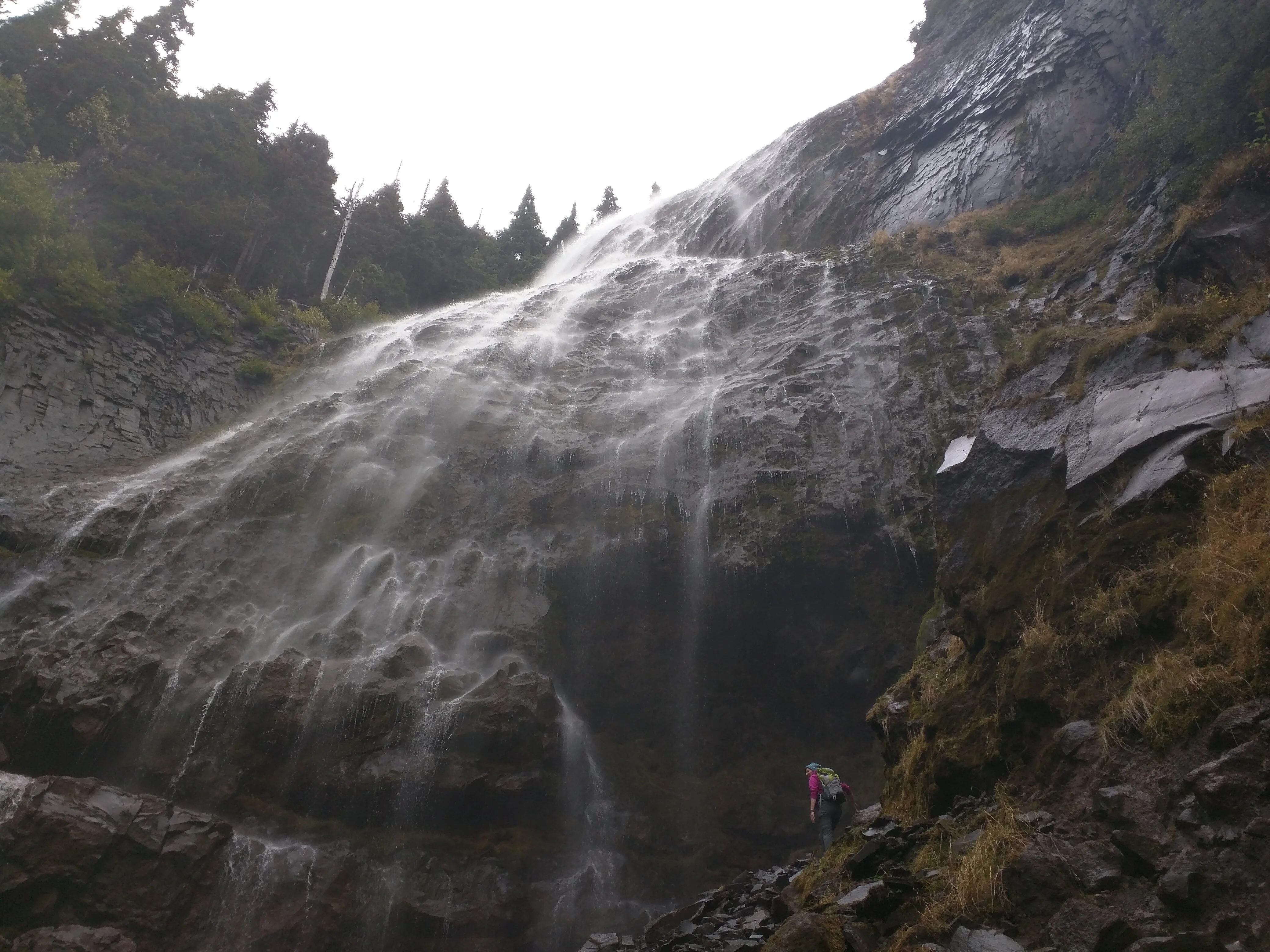 Stacy stands among rocks beneath the towering flow of Spray Falls.
