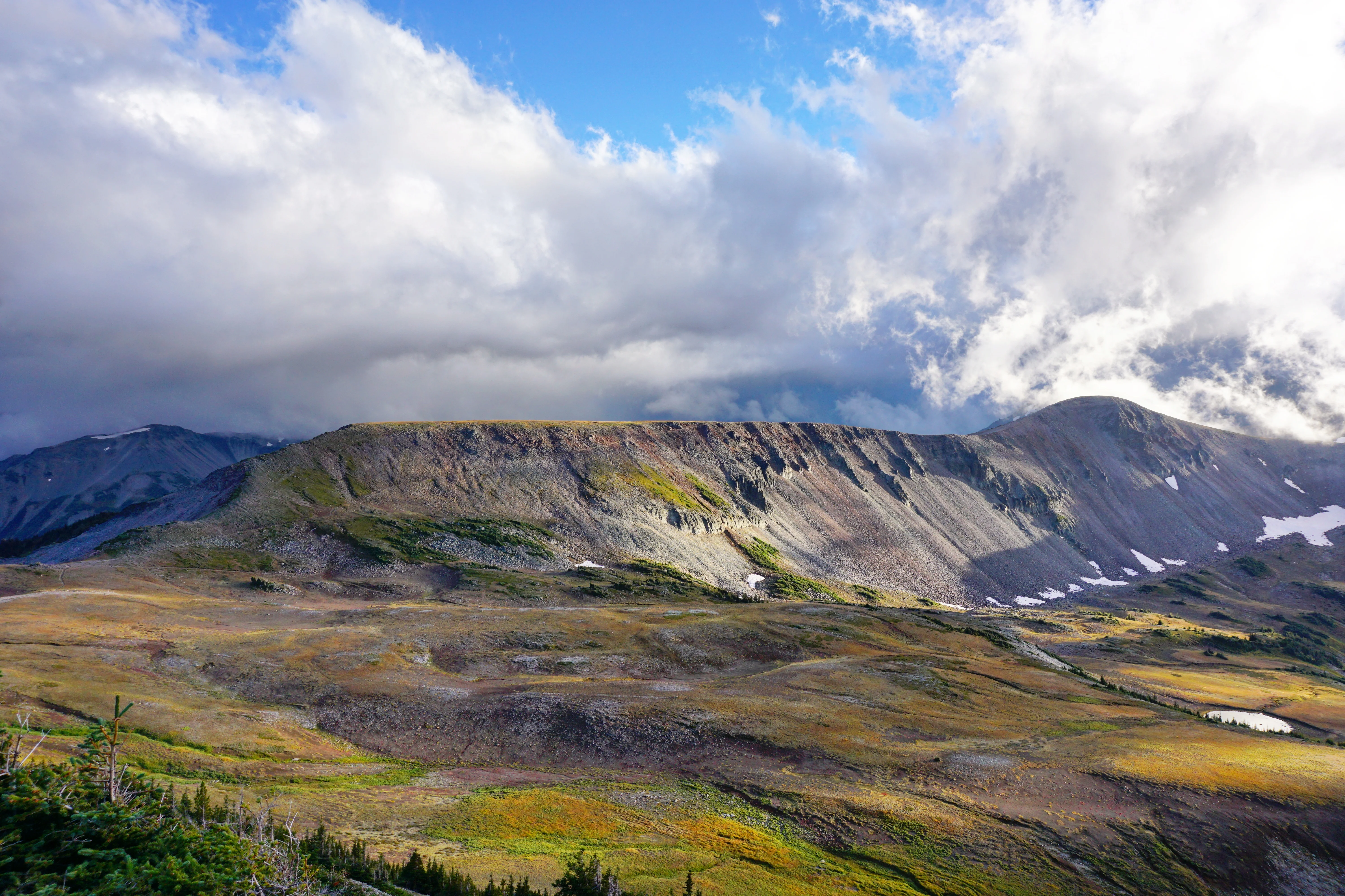 Burroughs Mountain rises across a rocky landscape beneath a partly cloudy sky.